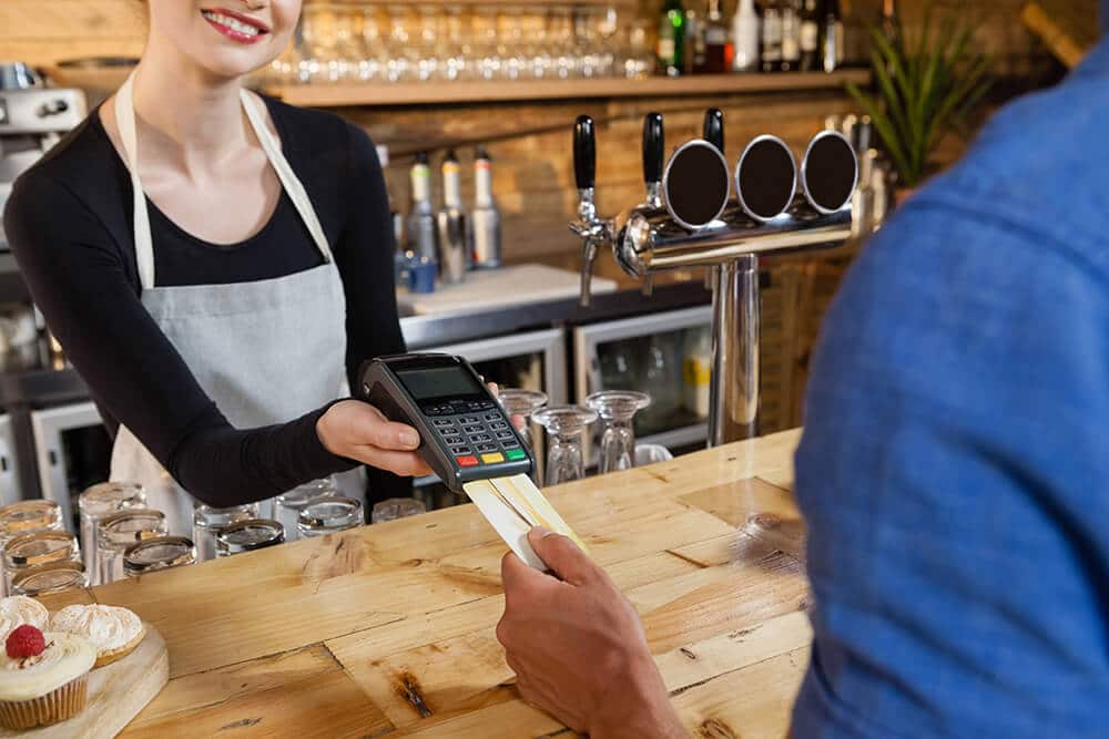customer making a payment through wireless credit card terminal at a coffee shop