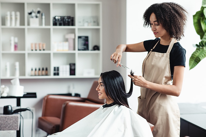 Young woman enjoying haircut at beauty salon