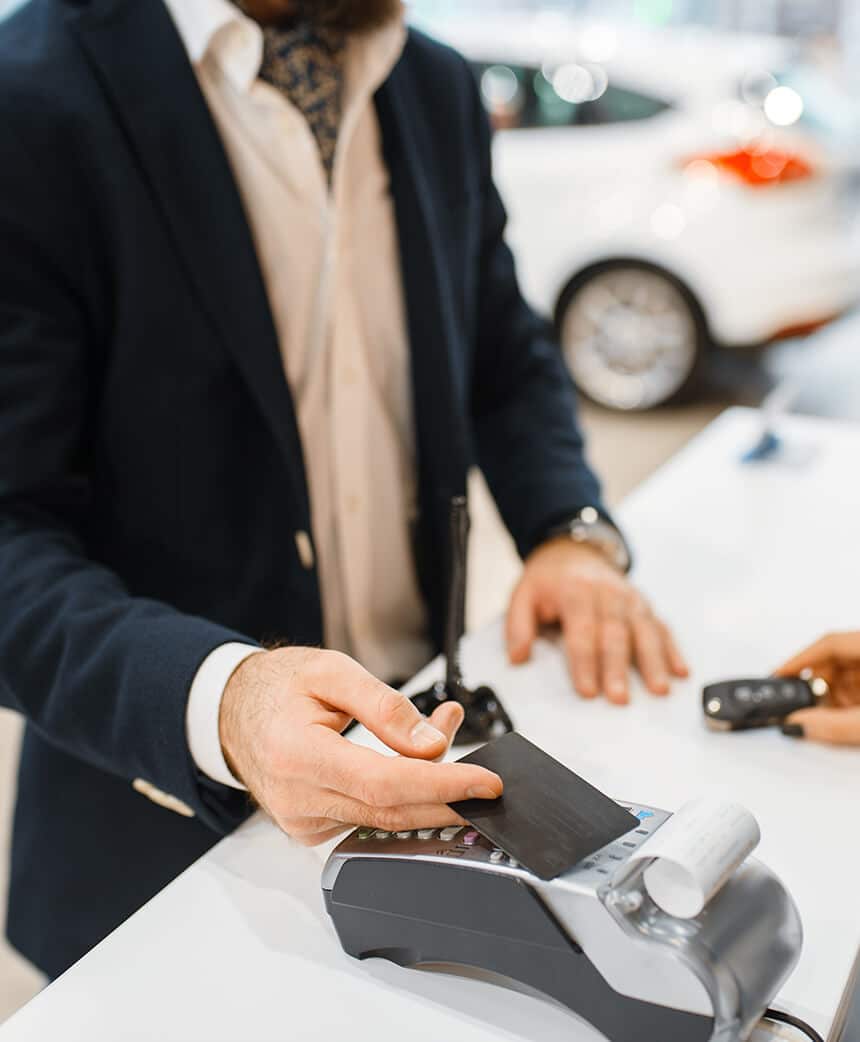 man paying for a new car on credit card terminal
